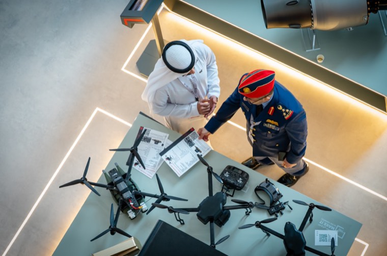 A military delegate and exhibitor discussing several drone systems