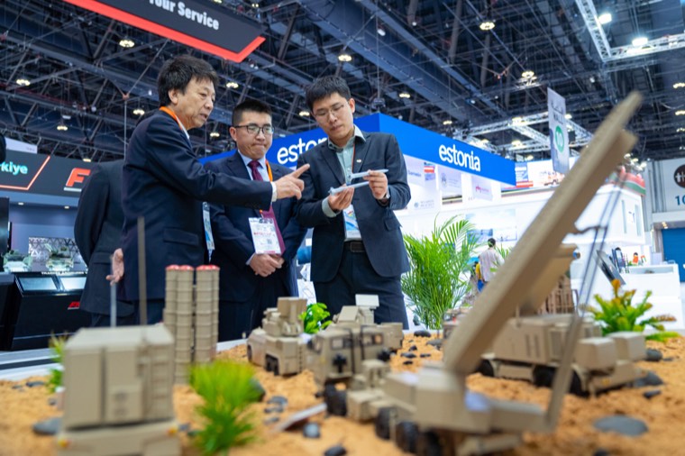 International exhibitors explaining a defence system model to a visitor