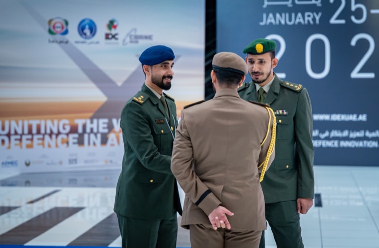 Uniformed delegates speaking together inside the IDEX venue